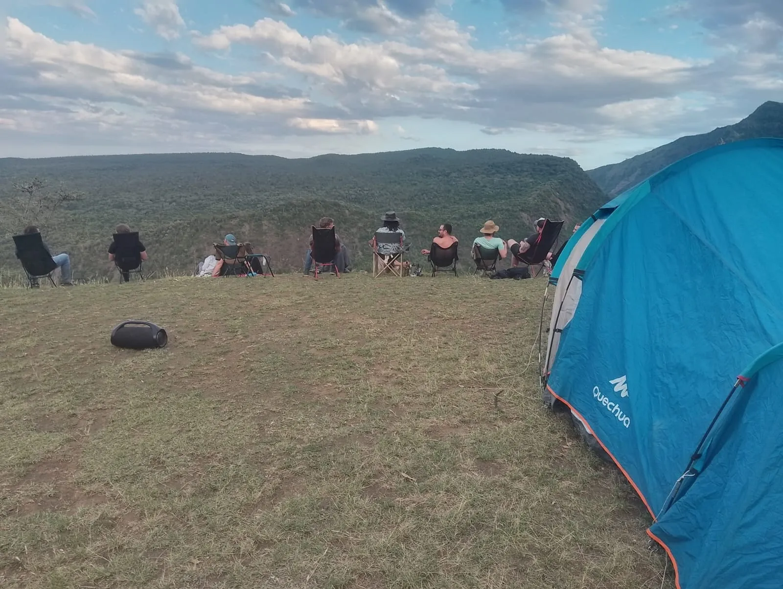 Guests in camping chairs on the crater rim next to a tent