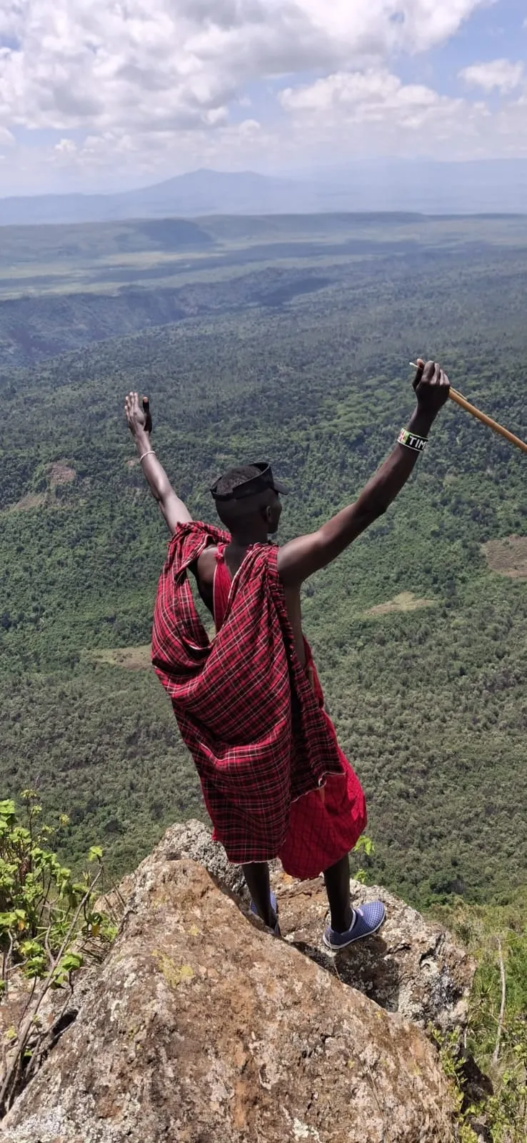A guide with his arms raised above the crater