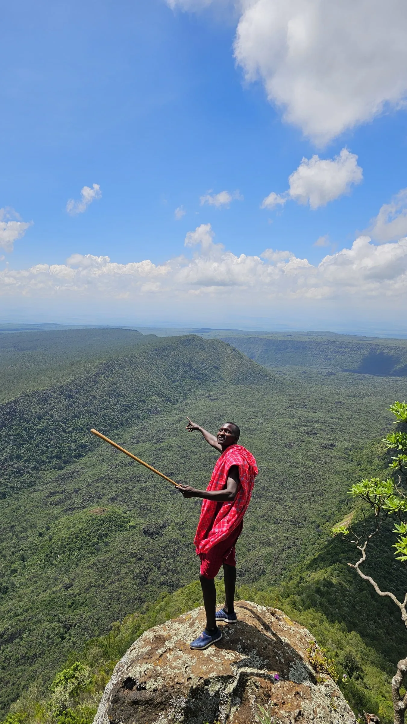 A Maasai guide on the crater rim of Mount Suswa pointing across the forested crater